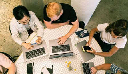 Photo of teenagers working at laptop computers around a table