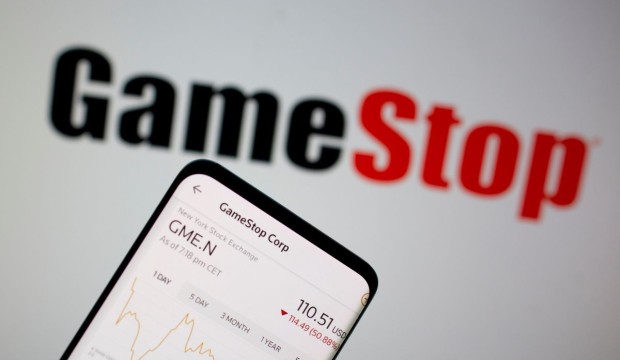 GameStop is laying off people as the company tries to fit in with a digitally-transforming videogame industry. In photo: GameStop stock graph is seen in front of the company's logo in this illustration taken February 2, 2021.